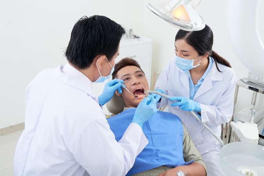 male-dentist-nurse-examining-asian-patient-s-teeth-clinic